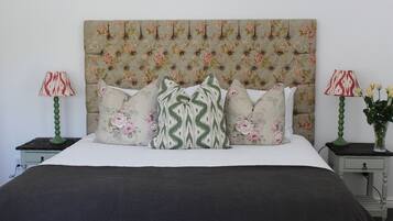 A bed with a floral headboard, multiple pillows, and two bedside tables with lamps.