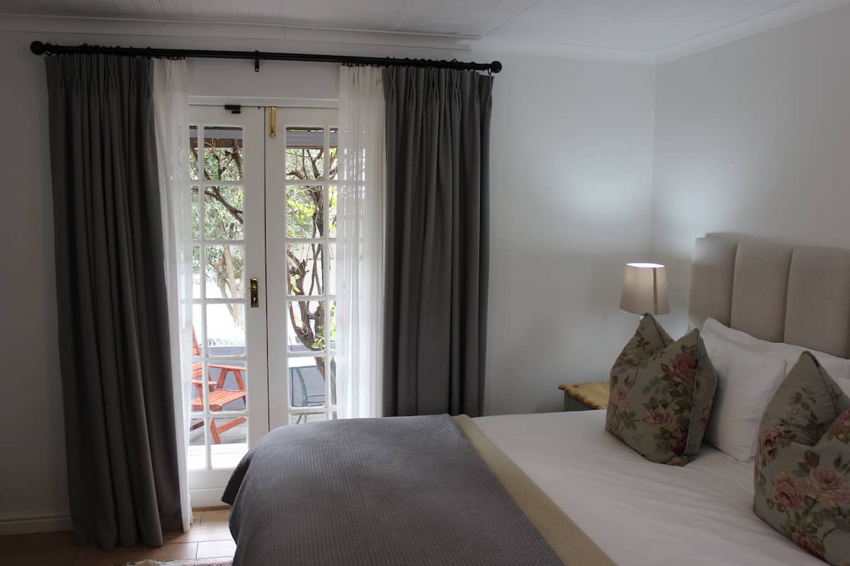 A bedroom with a bed, curtains, a lamp, and a view through a door.