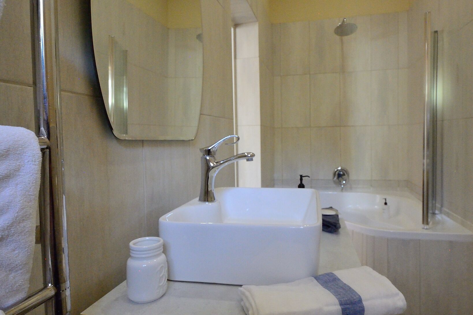 Un bagno con lavandino bianco, specchio, asciugamano e zona doccia.