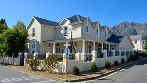 A large, two-story building with a sign reading "Le Petit Paris Guest House" on the facade. - Le Petit Paris (Franschhoek)