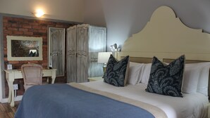 A bedroom with a large bed, a desk, a chair, and a wardrobe. - Le Petit Paris (Franschhoek)