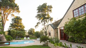 Un patio trasero con piscina, una casa de ladrillo y un césped.