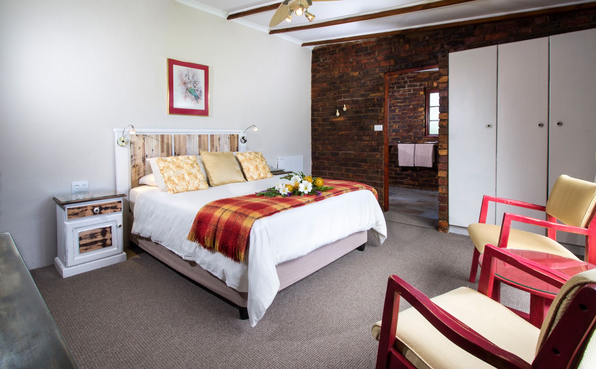 A bedroom with a bed, a nightstand, a chair, a wardrobe, and a brick wall.