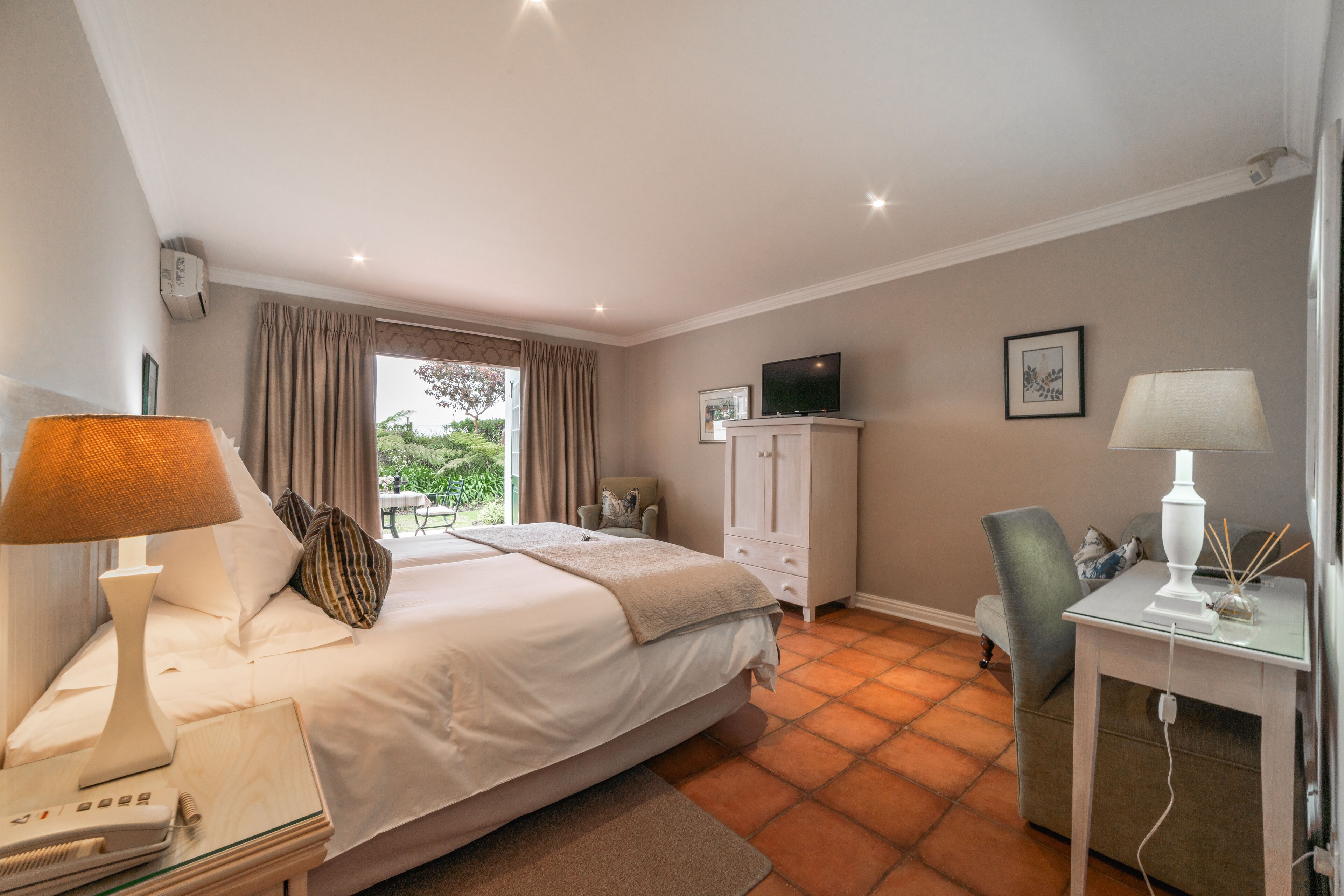 A bedroom with a bed, bedside table, lamp, and a desk with a lamp.