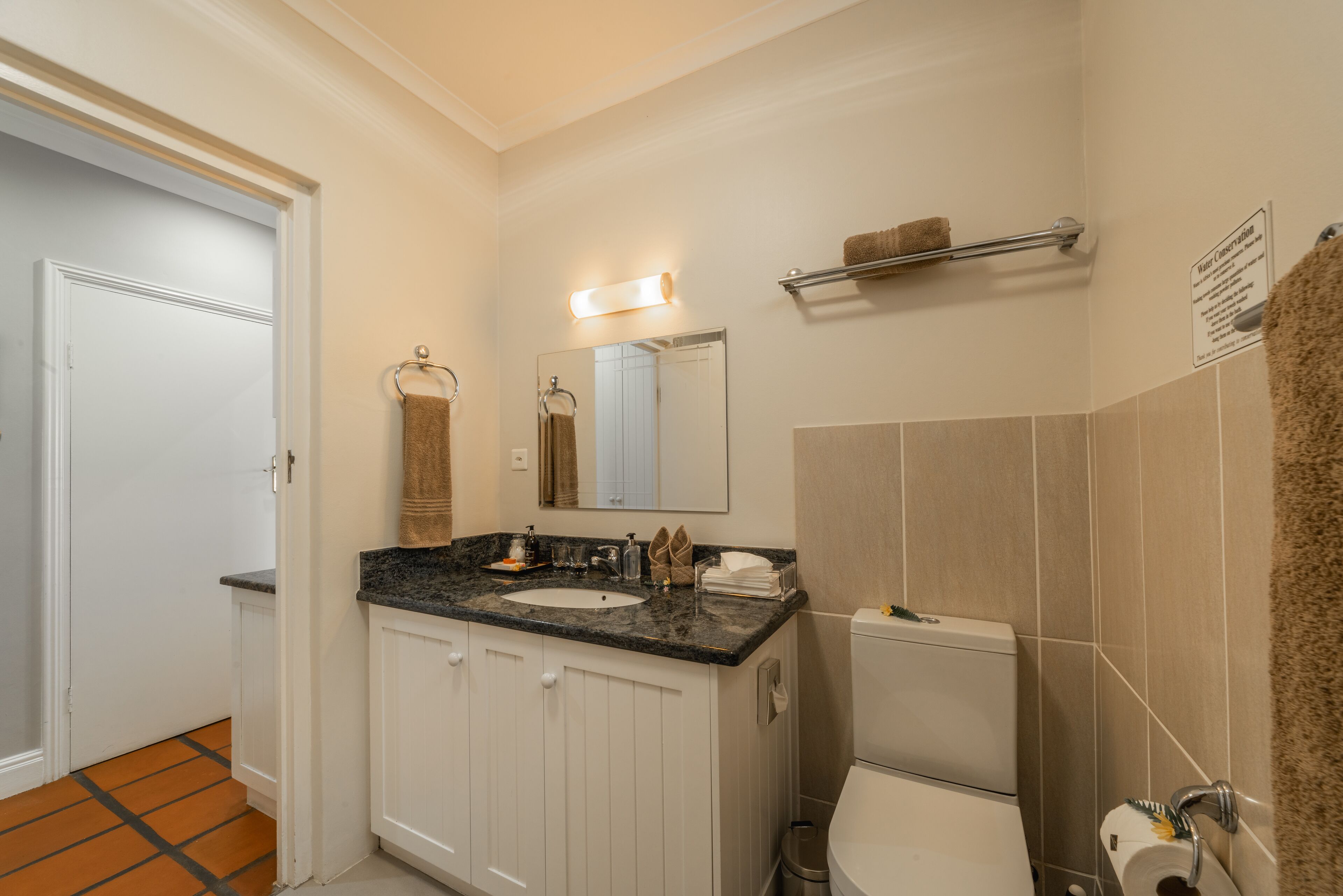 A bathroom with a white sink, a mirror, a towel rack, and a toilet.