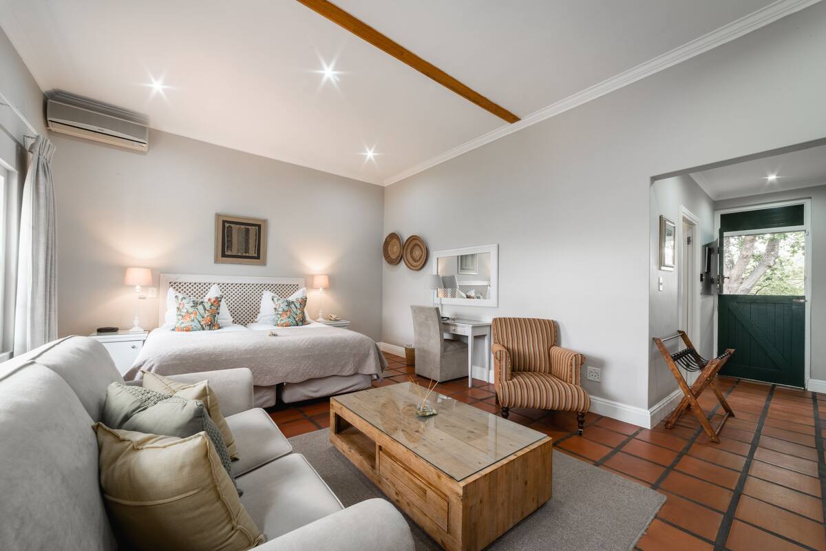 Una habitación bien iluminada con una cama, un sofá, una mesa de centro, un escritorio y una silla.