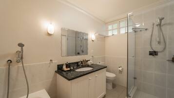 Une salle de bain équipée d’une baignoire, d’un lavabo, de toilettes et d’une douche séparée par des parois en verre.