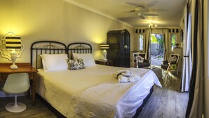 A well-lit bedroom with a large bed, bedside tables, a desk, and a chair. There is a window with curtains and a view of the outdoors.
