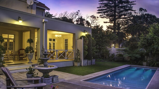 A modern house with a swimming pool, outdoor seating, and a well-maintained garden.