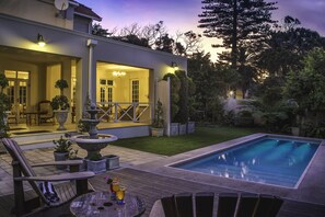 A modern house with a swimming pool, outdoor seating, and a well-maintained garden.