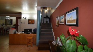 A reception area with a desk, computer, and a staircase leading to an upper floor. - Broadway Tygervalley (Cape Town)