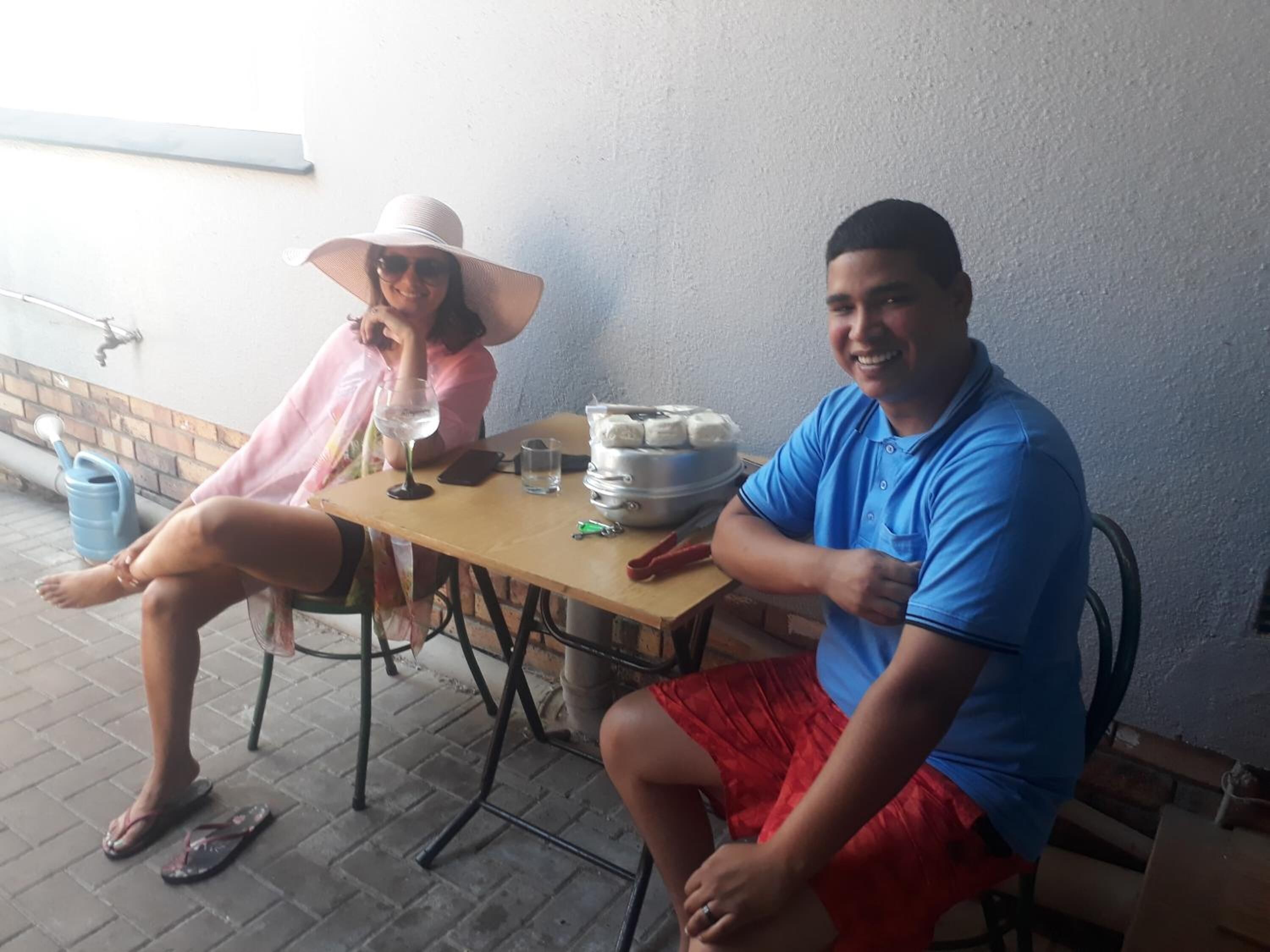 Two people sitting at an outdoor table with a drink and snacks.