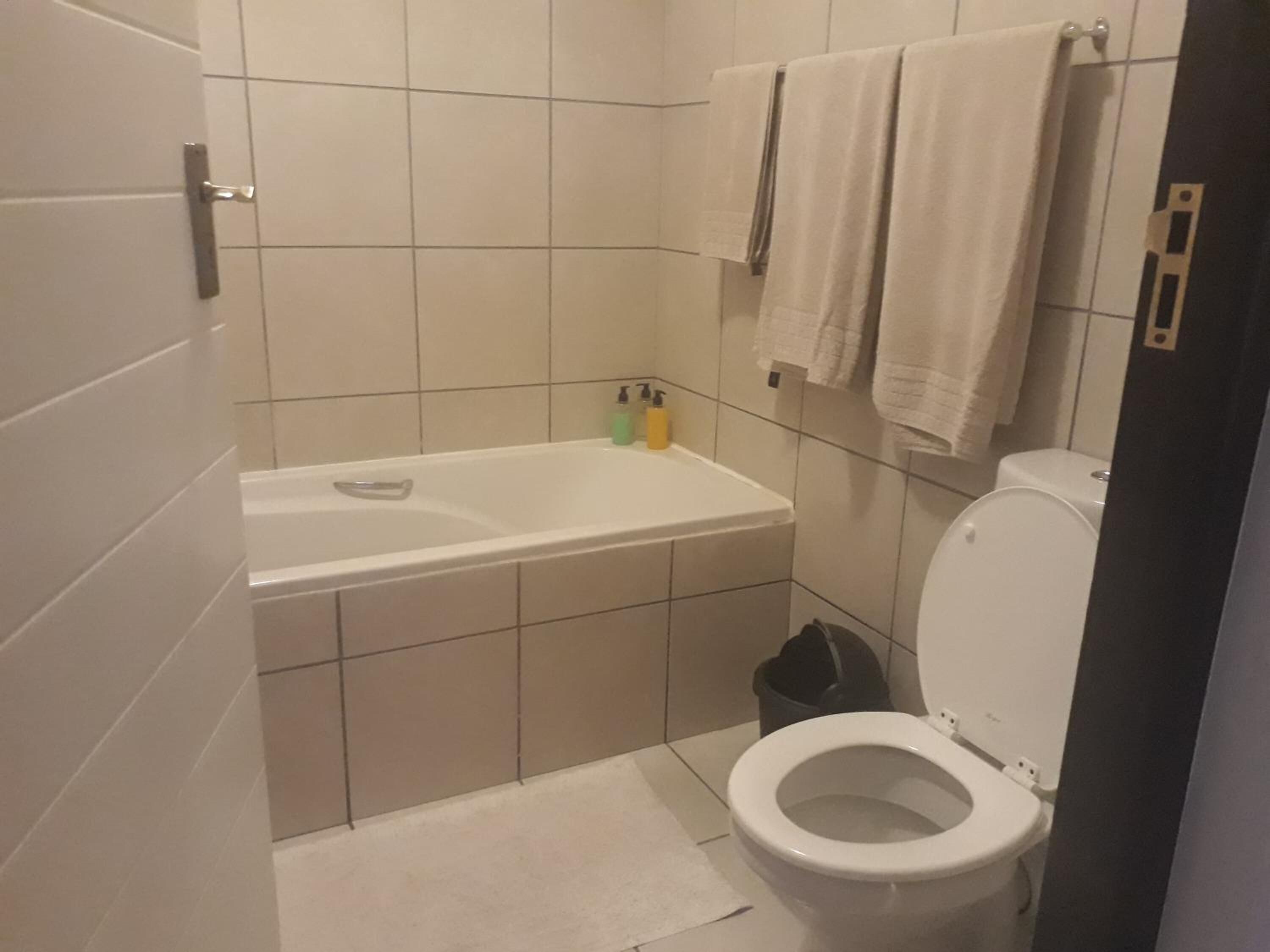 Ein Badezimmer mit Badewanne, Toilette und einem kleinen Mülleimer.