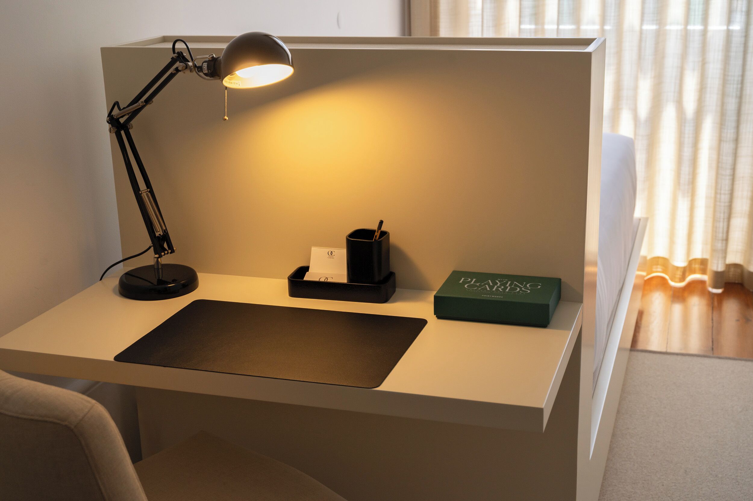 A desk with a desk lamp, a black cup, and a green box labeled "PLANS."