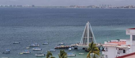 A coastal view with a bridge, boats, and a beach with palm trees.