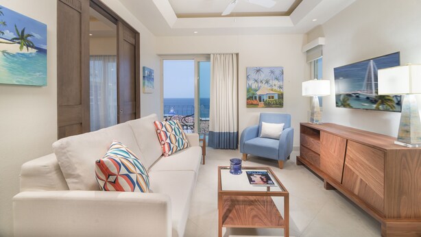Una sala moderna con sofá, sillón, mesa de centro y mueble para televisión.