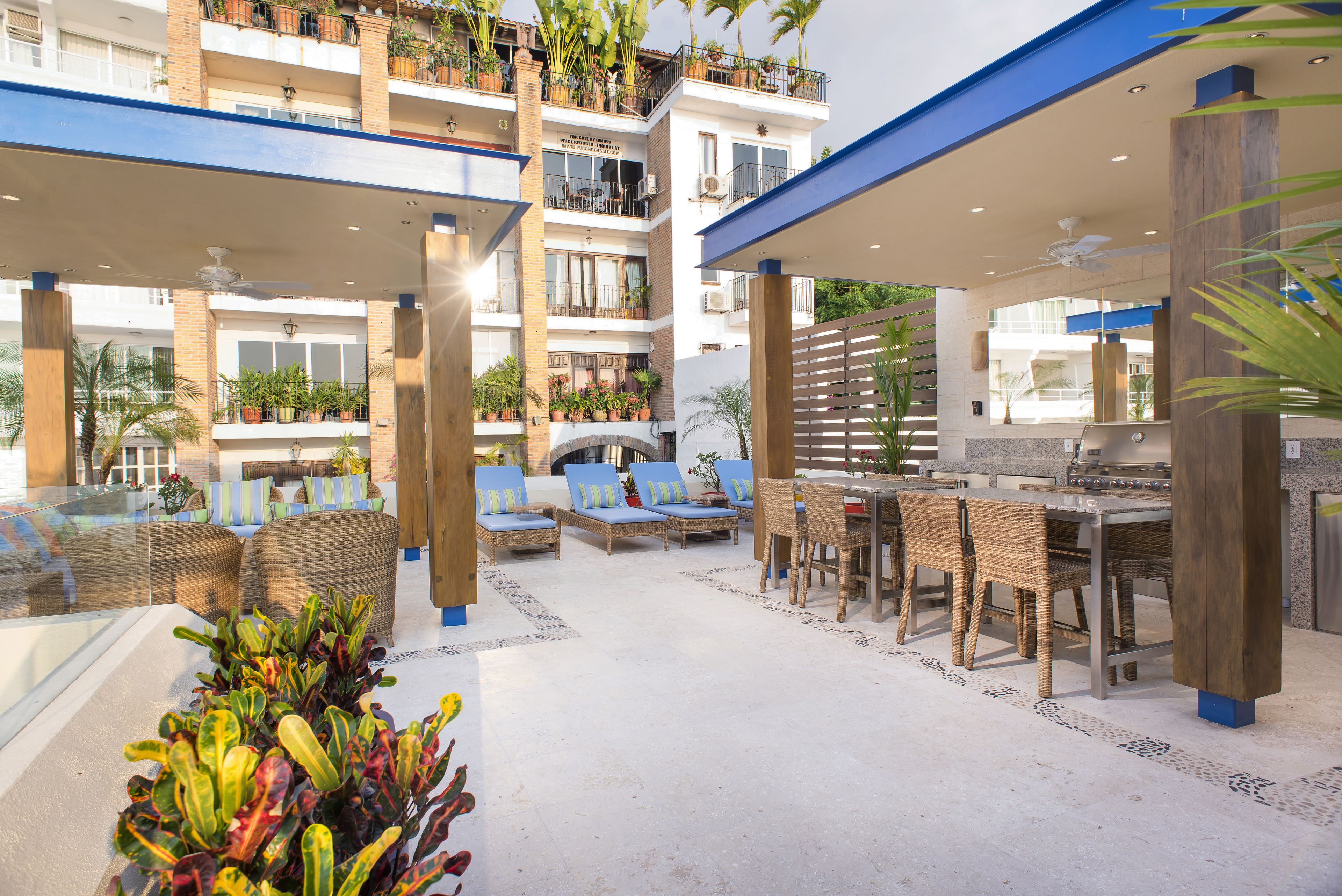 A rooftop patio with outdoor furniture, a dining area, and a view of the building's balconies.
