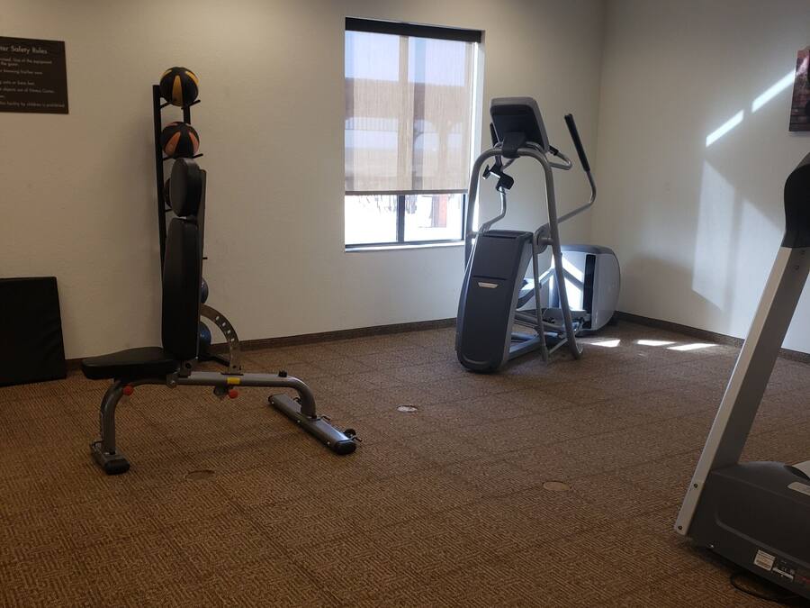 A fitness room with exercise equipment, a window, and a carpeted floor.