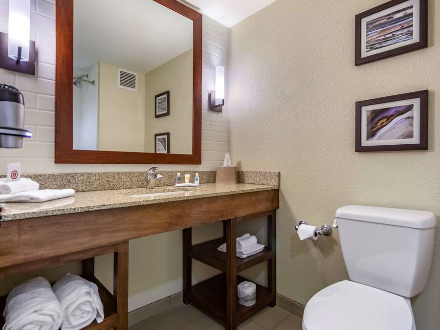 A bathroom with a wooden vanity, a sink, a toilet, and two framed pictures on the wall.