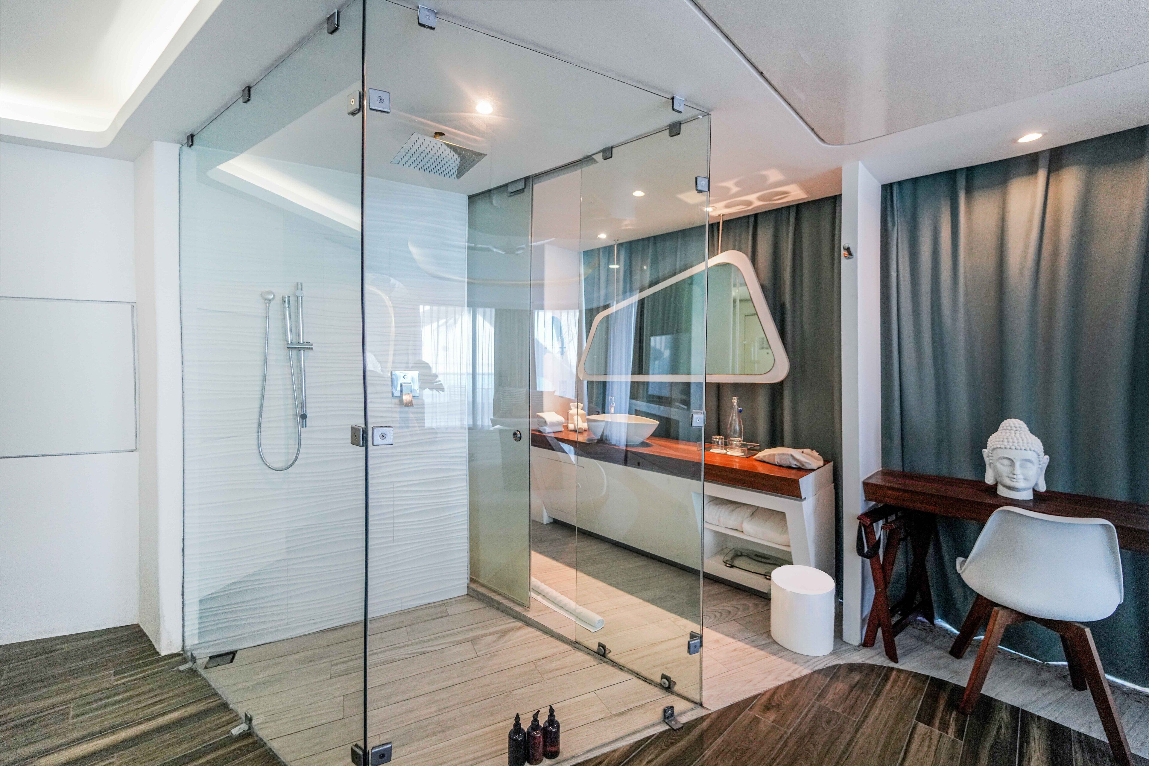 Une salle de bain moderne avec une douche à parois de verre, un meuble-lavabo avec un miroir et une statue de Bouddha.