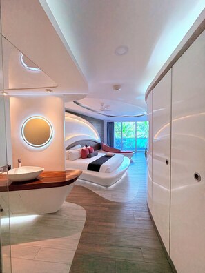 A modern bedroom with a curved bed, a round mirror, and a large wardrobe.