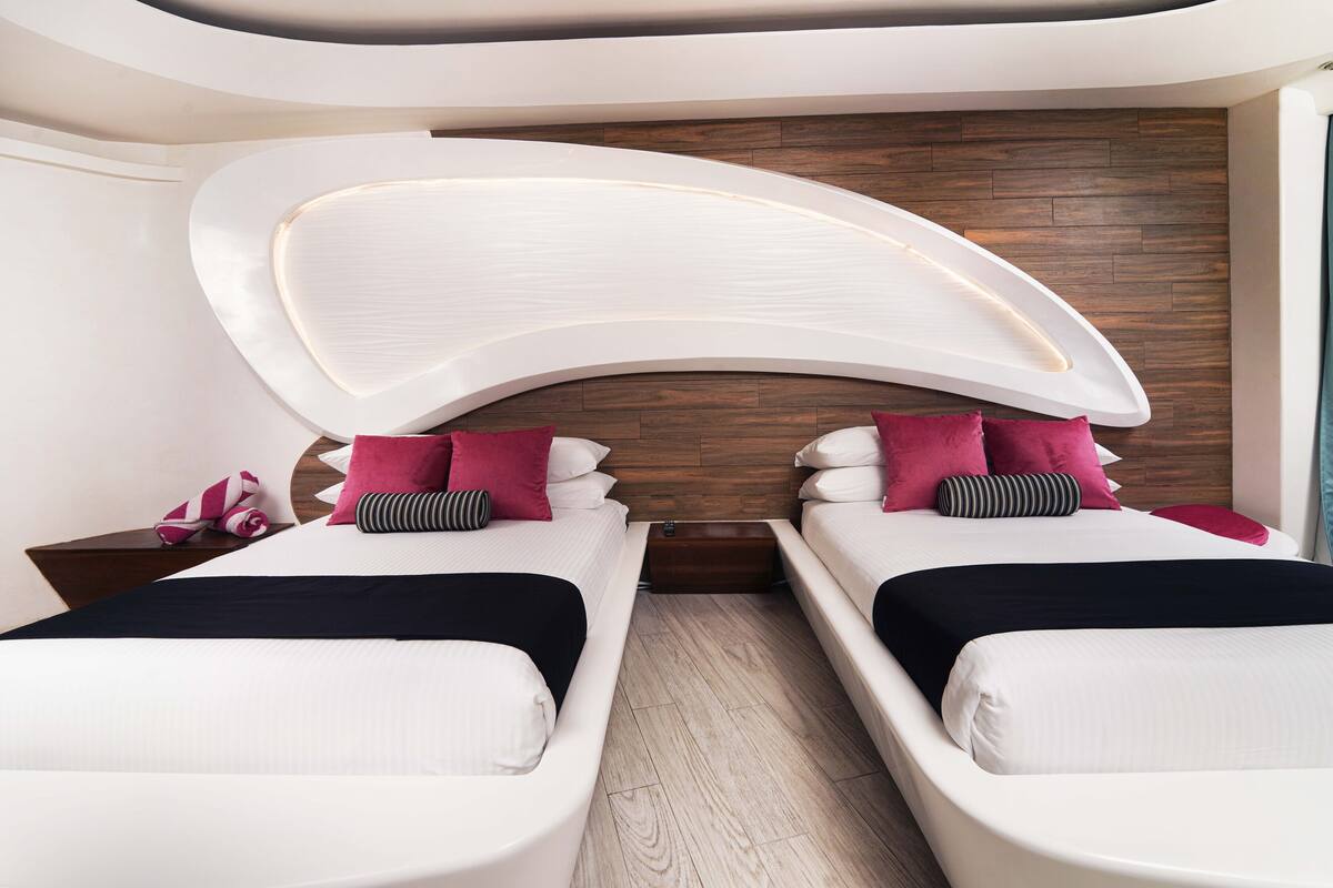 Ein modernes Hotelzimmer mit zwei Betten, einem geschwungenen Deckenbau und einer Holzwand.