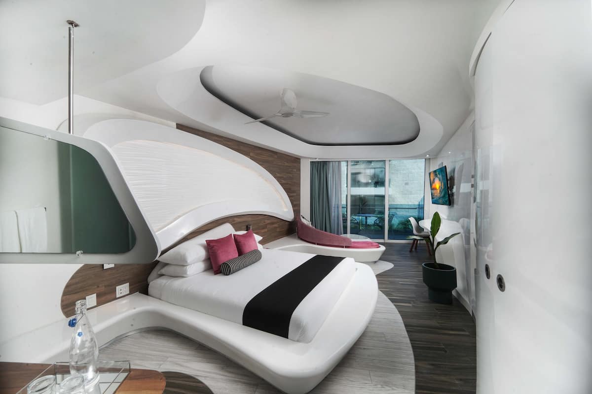 Ein modernes Schlafzimmer mit einem gewölbten Bett, einem großen Fenster und Blick ins Freie.