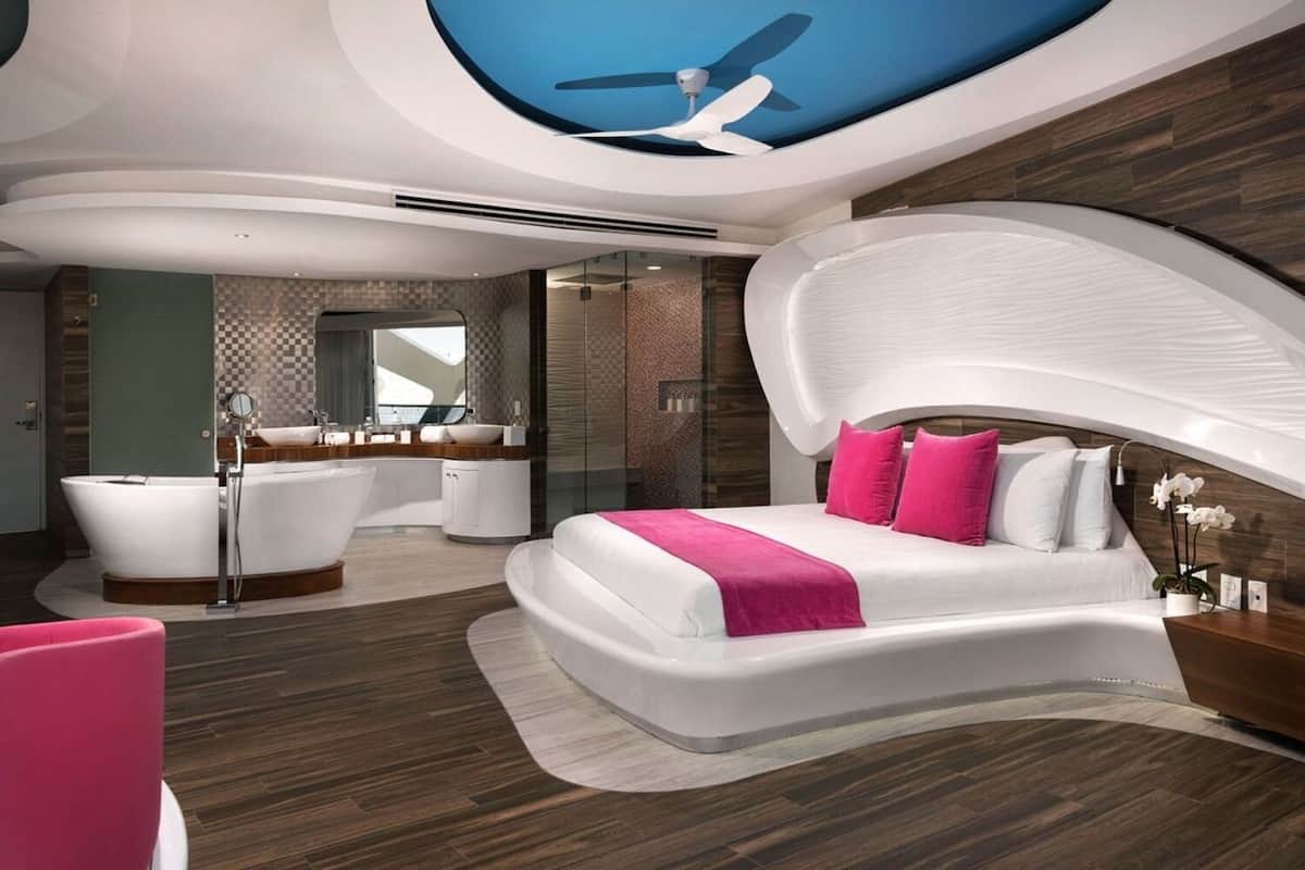 Ein modernes Schlafzimmer mit einem bogenförmigen Bett, einem großen Fenster und einem Deckenventilator.