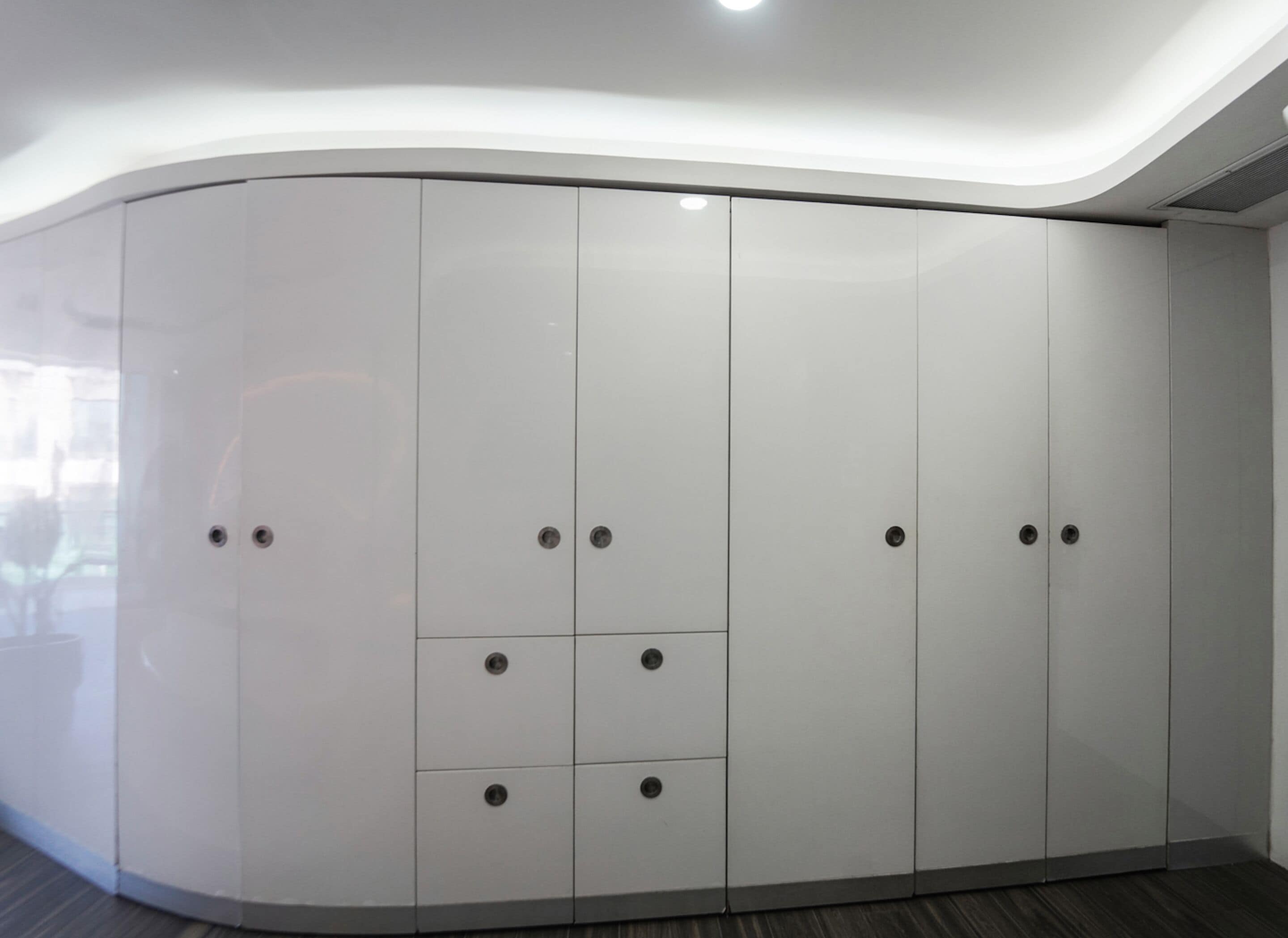 Un armario moderno de líneas curvas con múltiples puertas y cajones, que presenta un diseño elegante y minimalista.