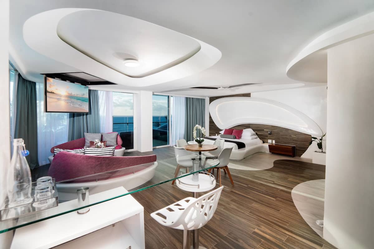 Ein modernes Wohnzimmer mit einem Glastisch, weißen Sofas und Meerblick.