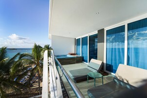Uma varanda com vista para o oceano, uma cama e um espaço de estar com vista para o mar.