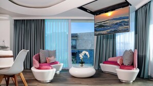 Un salon moderne avec deux canapés blancs, une table basse ronde et une grande fenêtre agrémentée de rideaux.
