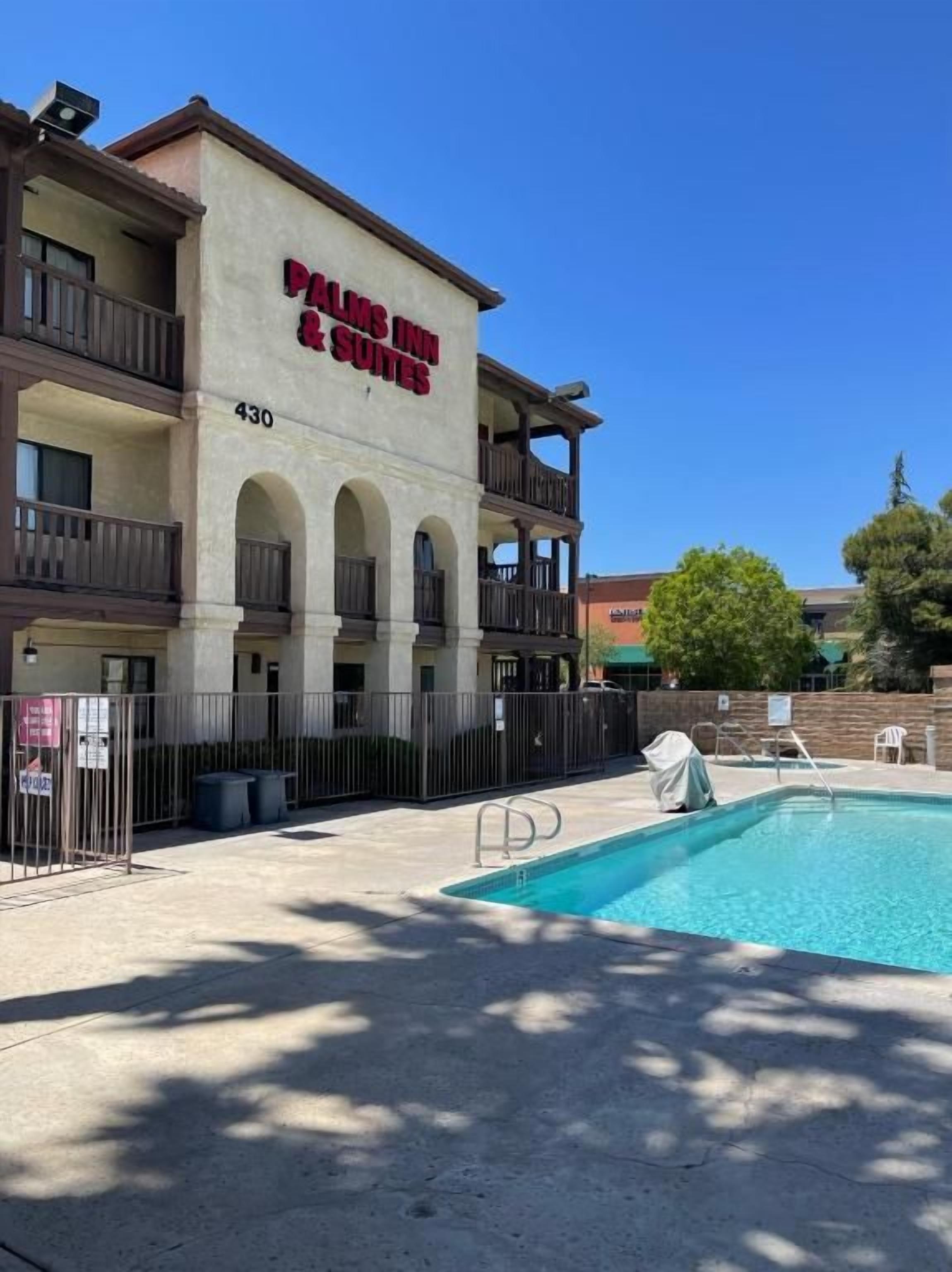 A hotel with a pool, outdoor seating, and a sign reading 'PALACE INN & SUITES.'