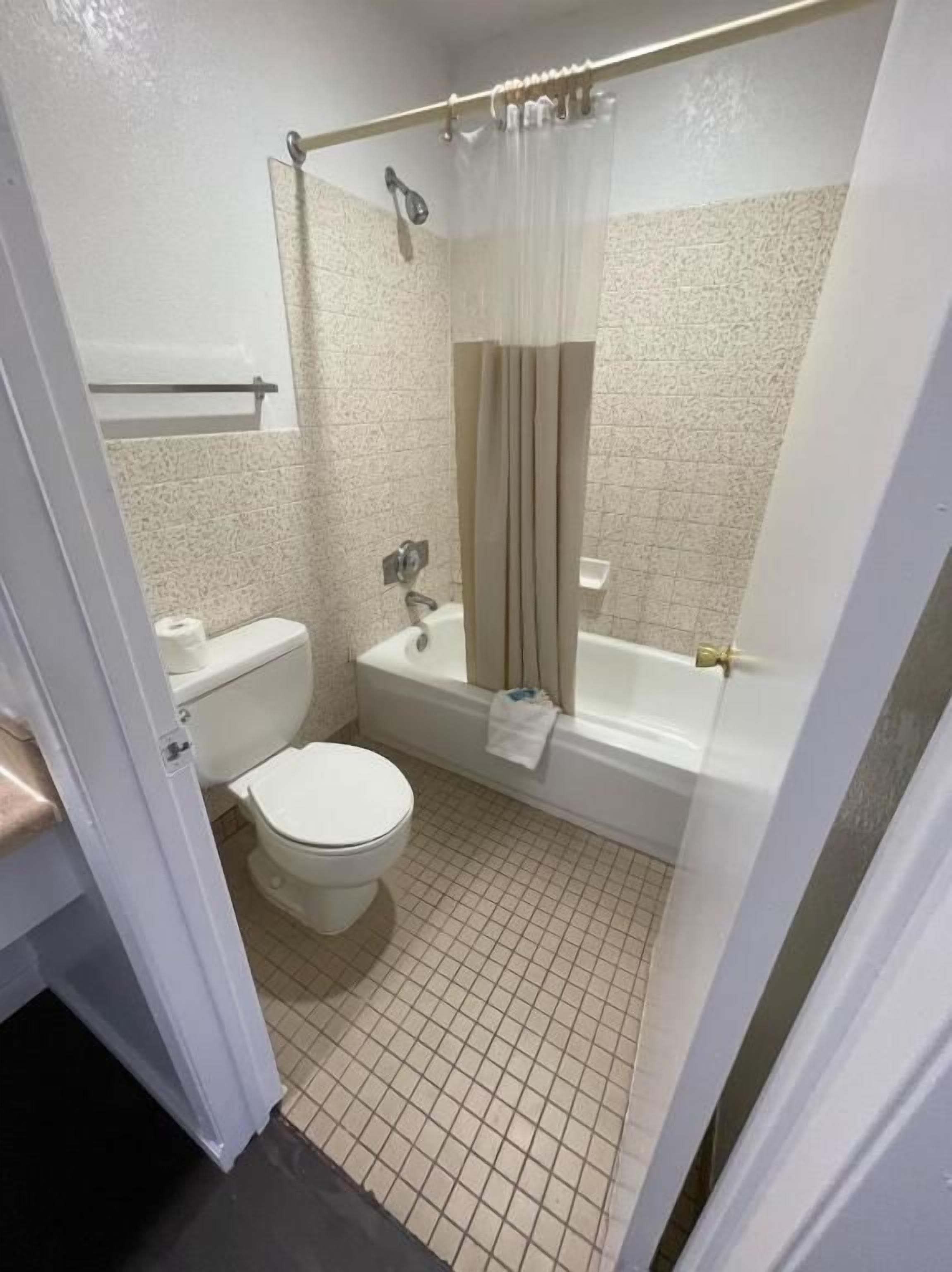 A bathroom with a toilet, sink, bathtub, and shower curtain.
