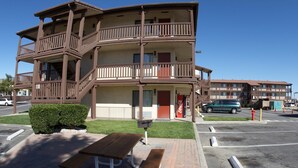 A multi-story motel with balconies, a Coca-Cola sign, and a picnic table in the parking lot. - Palms Inn & Suites (Palmdale)