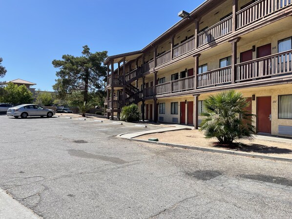 A multi-story motel with balconies, numbered rooms, and a parking lot. - Palms Inn & Suites (Palmdale)
