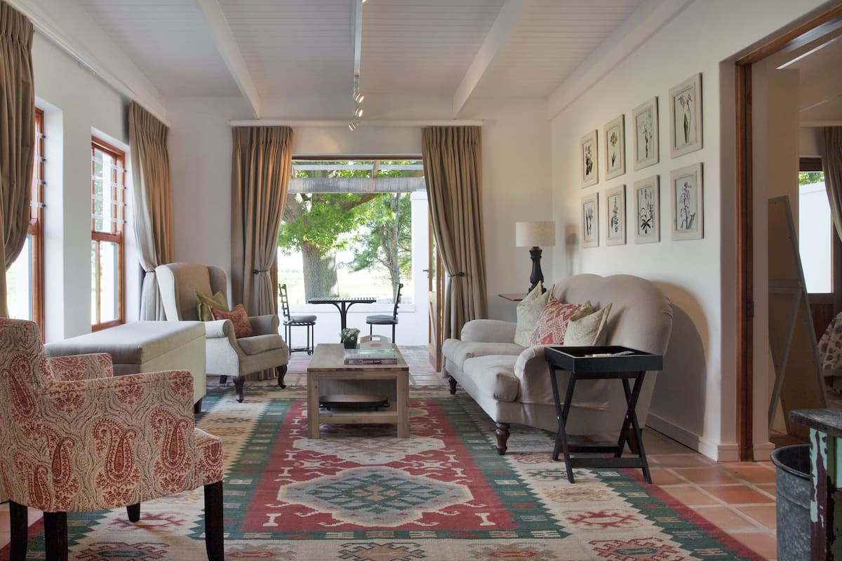 Una sala de estar con un sofá, sillones, una mesita de centro y un tapete estampado.