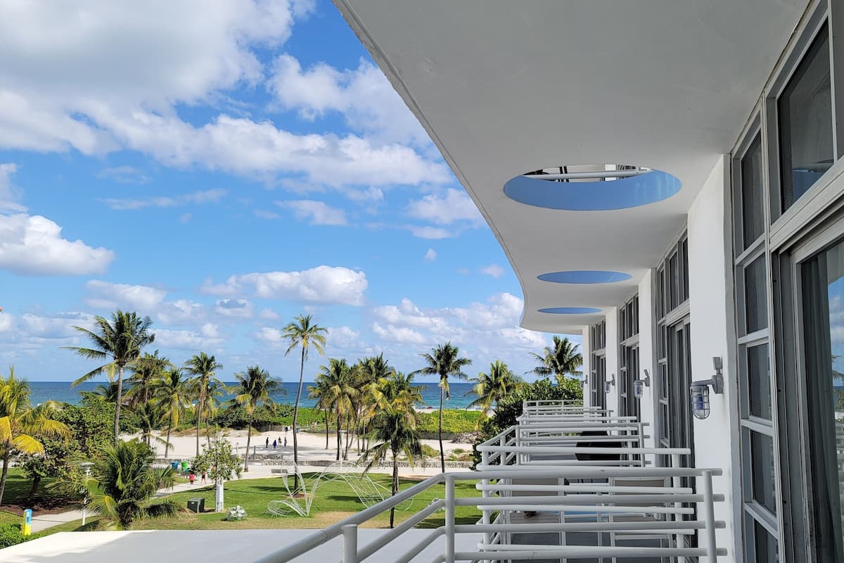 Un balcon moderne donnant sur l’océan et bordé de palmiers.