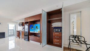 A modern kitchen with a built-in TV, wooden cabinets, and a microwave. - Strand Ocean Drive Suites (Miami Beach)