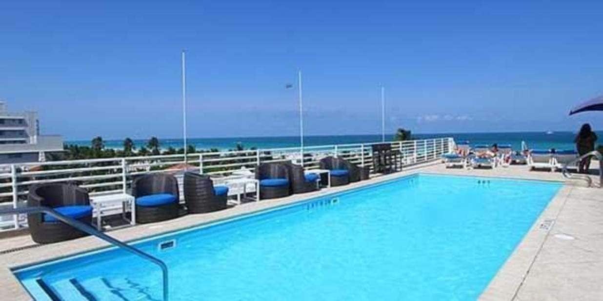 A pool area with lounge chairs and a view of the ocean.