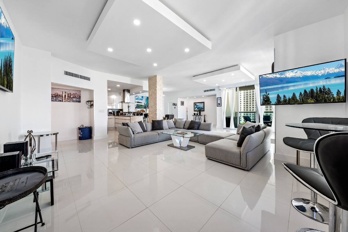 A modern living room with a sectional sofa, a glass coffee table, and a dining area with a table and chairs.