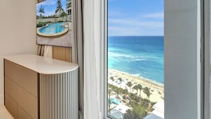 Quarto moderno com uma janela grande que oferece vista para a praia e oceano.