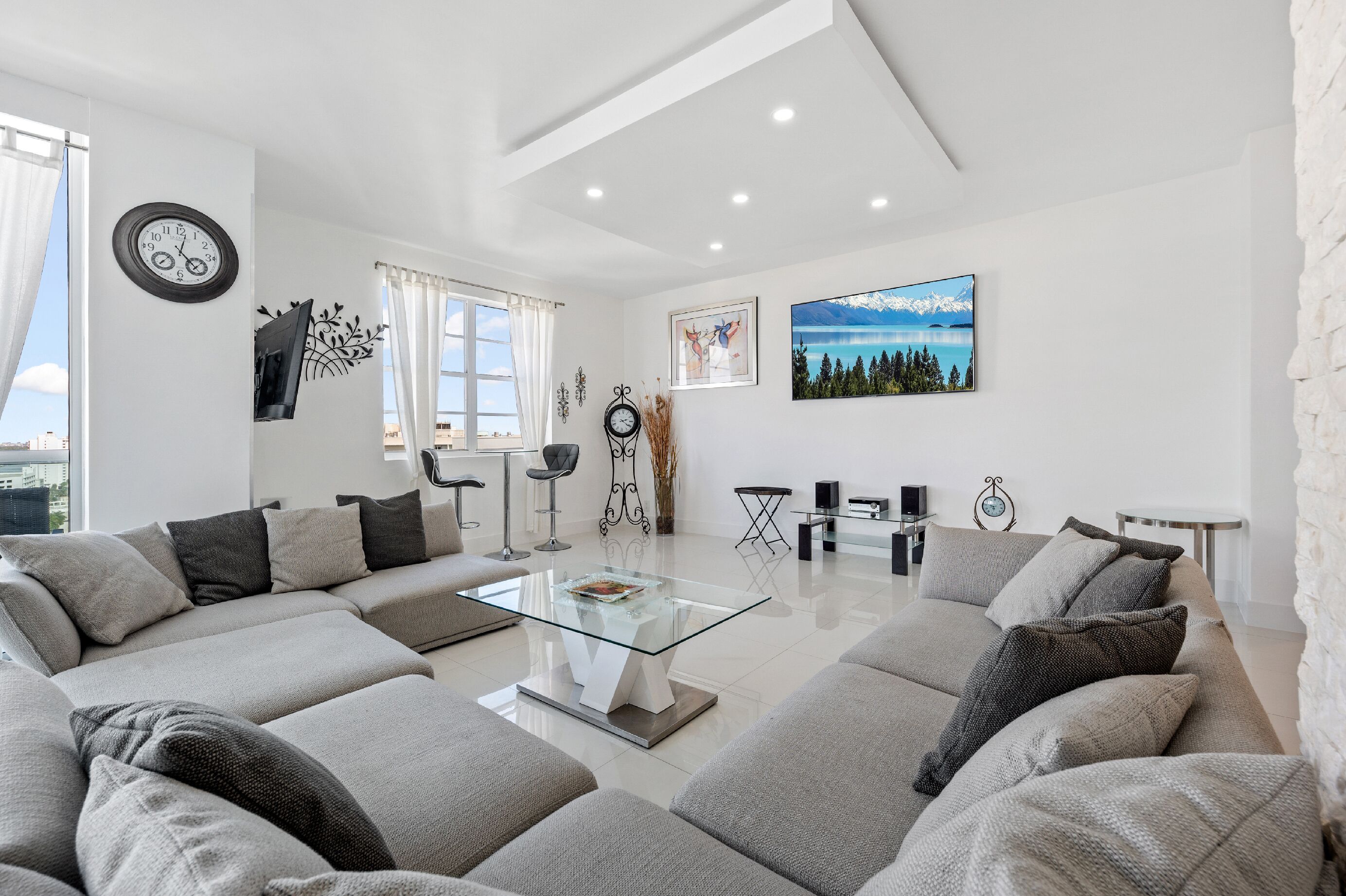 Una sala de estar moderna con un sofá modular, una mesa de centro de vidrio y un ventanal con cortinas.
