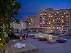 A rooftop pool area with lounge chairs and a jacuzzi, surrounded by a high-rise building with illuminated windows. - ABAE Hotel by Eskape Collection  (Miami Beach)