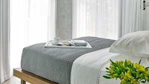 A modern bedroom with a bed, a bedside table, a lamp, and a vase with flowers.