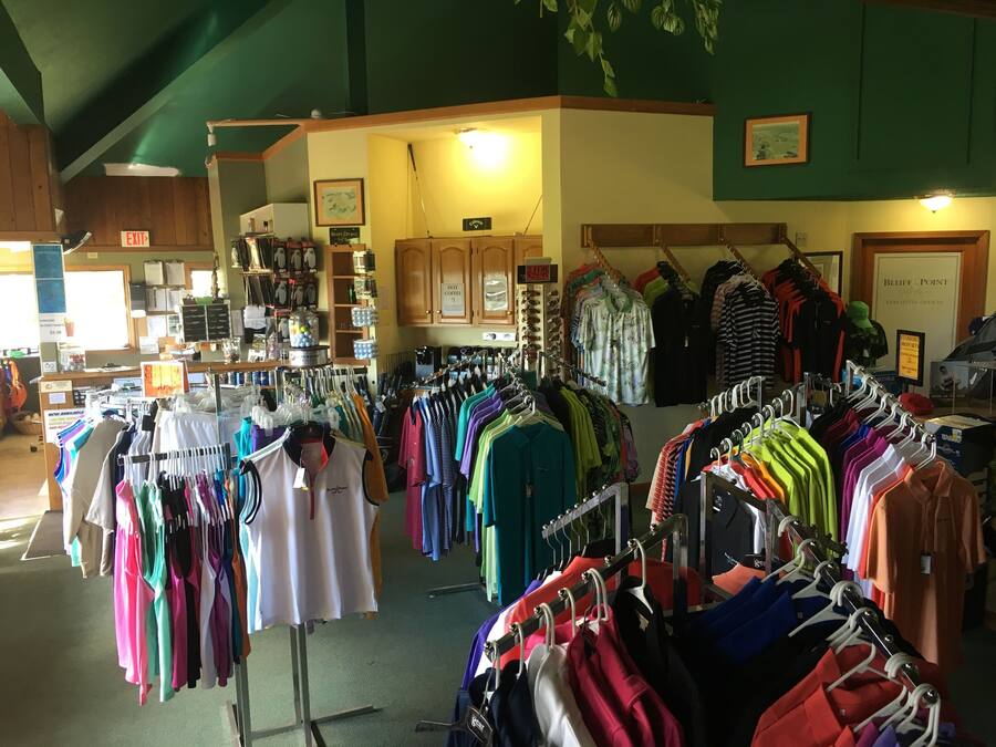 A clothing store with racks of colorful shirts and pants, a coffee shop area, and a sign for 'Bluff Point Executive Offices'.