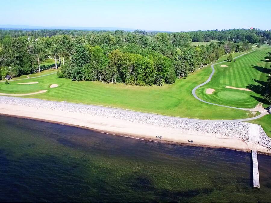 A golf course with a beach and forested area.