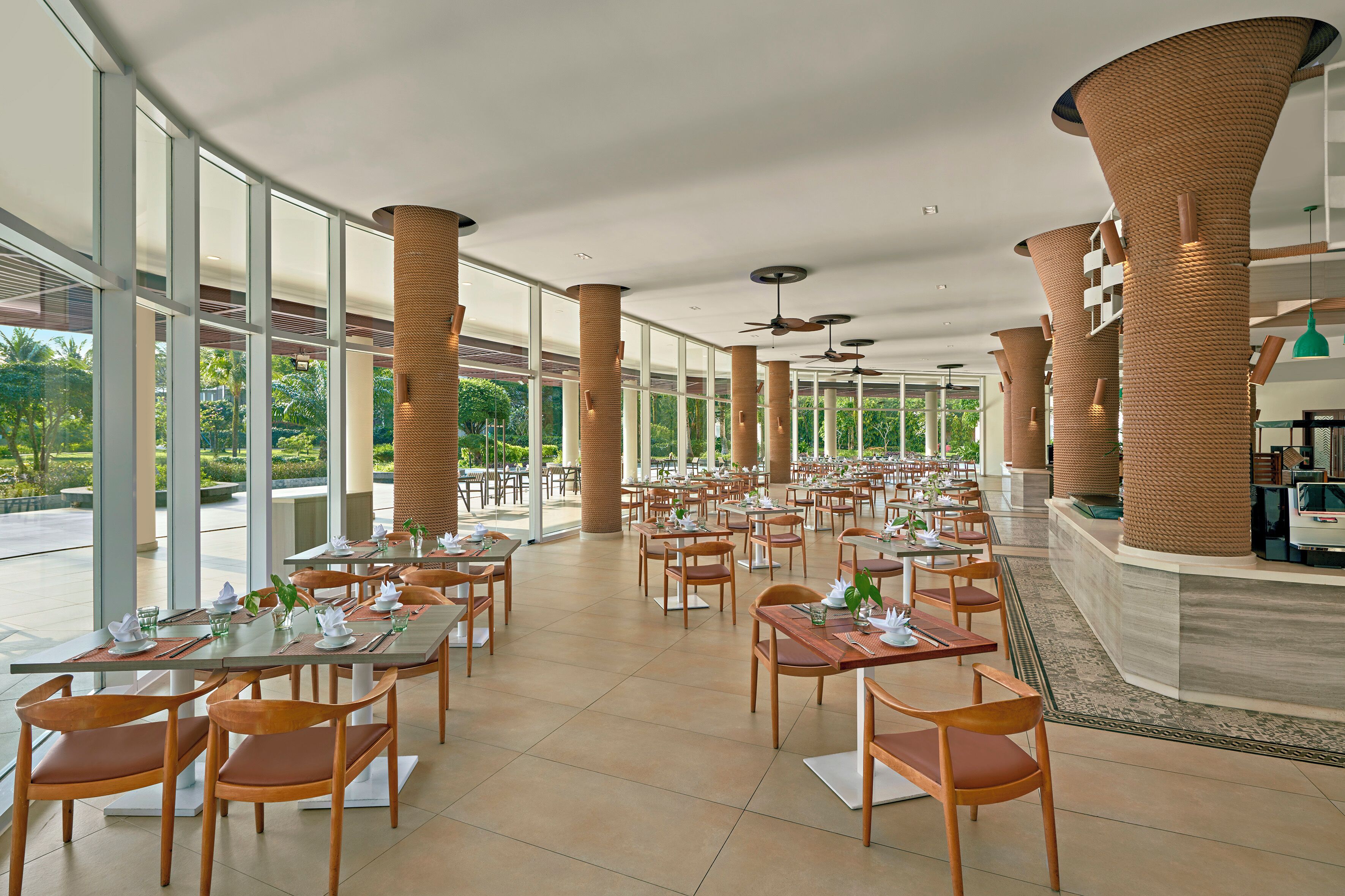 A spacious dining area with high ceilings, large windows, and modern furnishings.