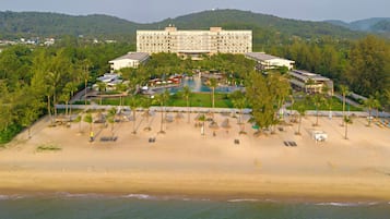 Un complexe hôtelier comprenant un grand bâtiment, une piscine et une plage.
