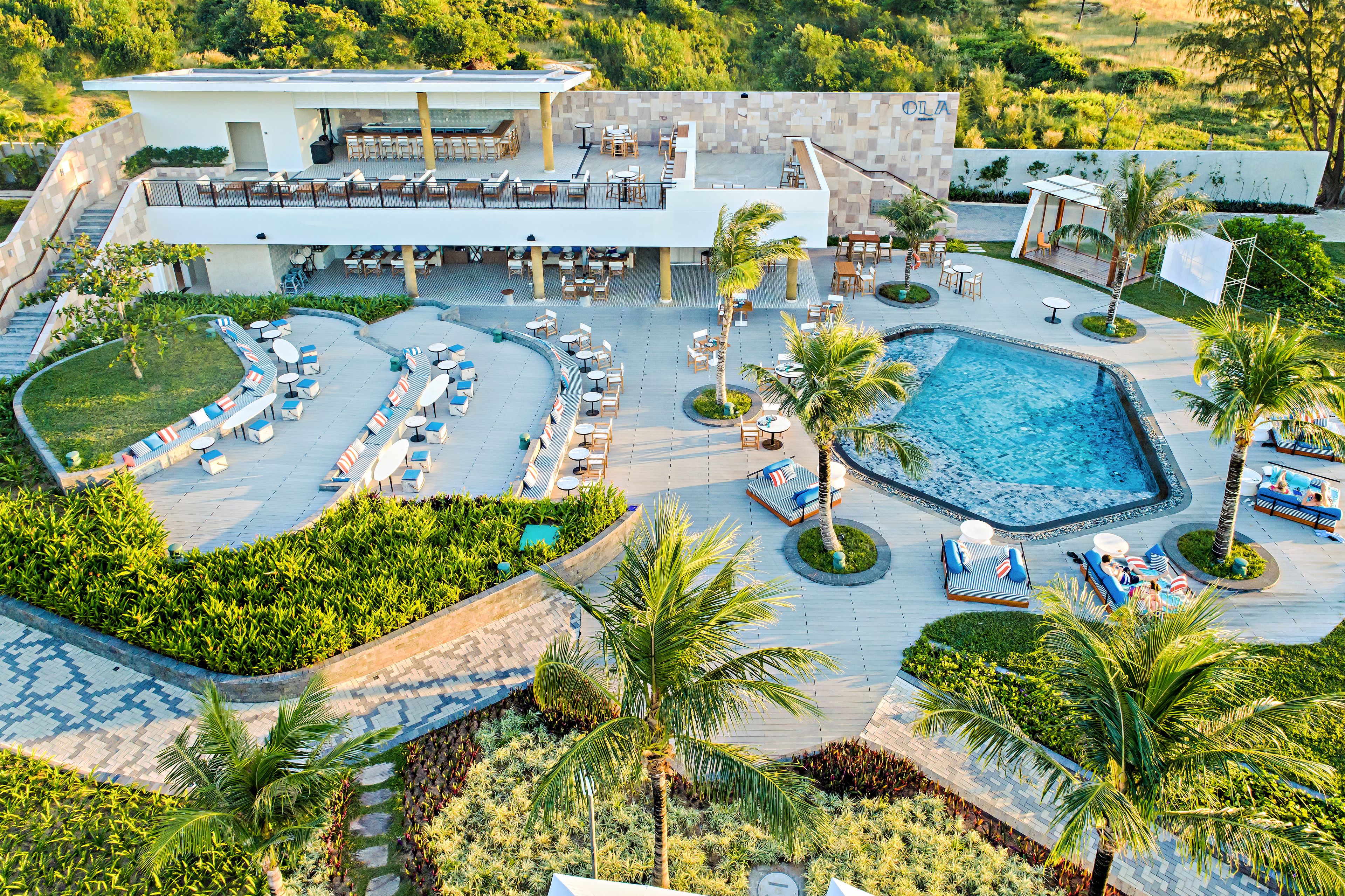 A resort with a swimming pool, outdoor seating areas, and a covered patio.